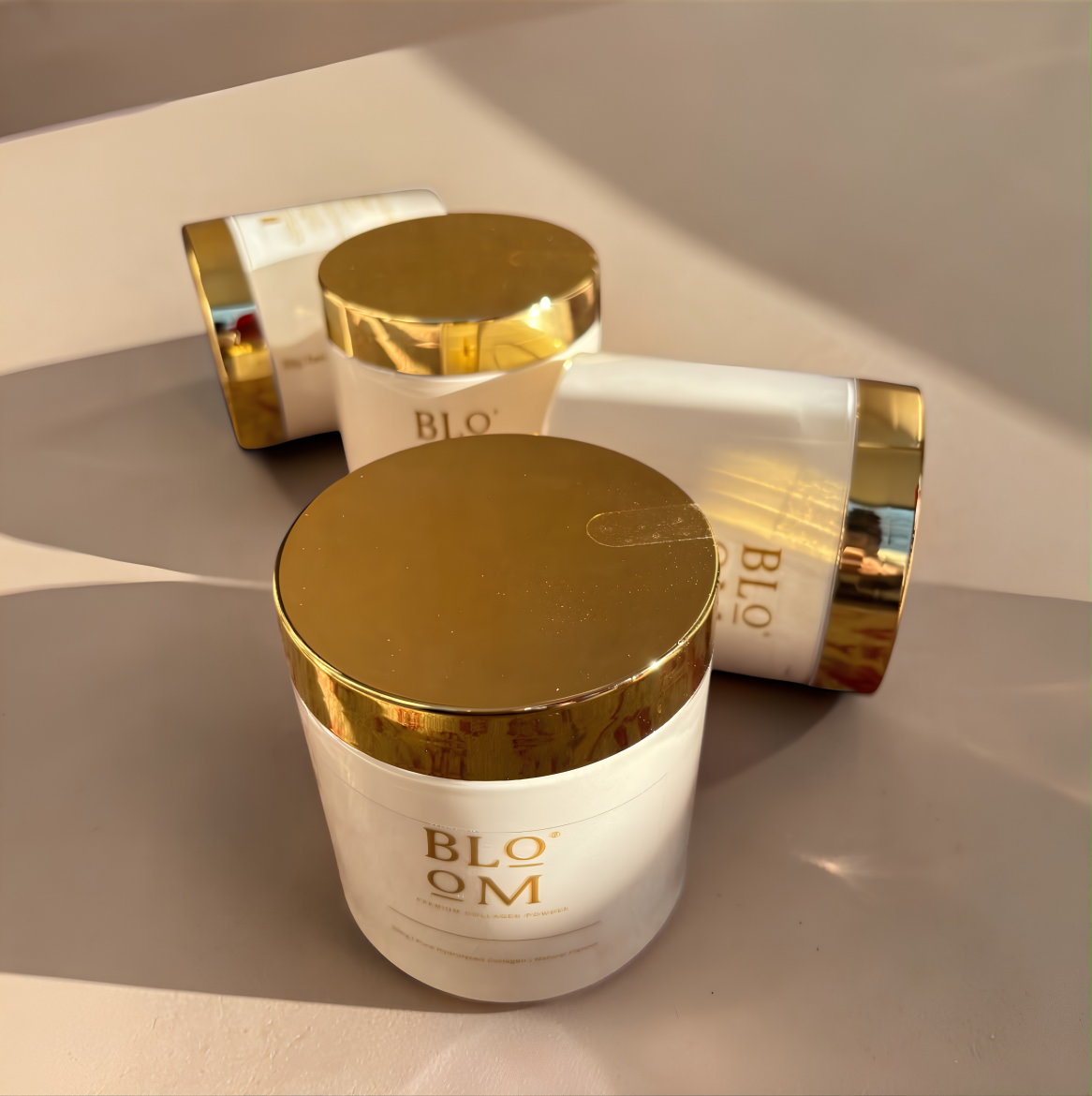 Close view of the Bloom collagen jar and its gold lid on a cream surface